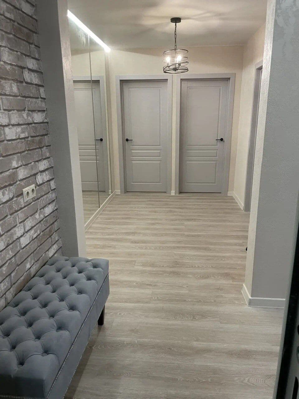 Коридор — декоративный кирпич, банкетка, серые двери, люстра