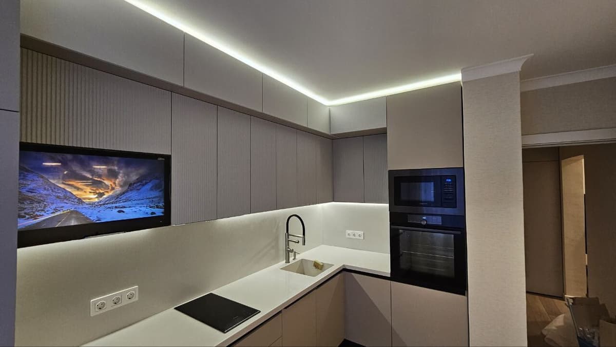 Общий вид кухни — рифлёные верхние шкафы, встроенный ТВ, LED-лента