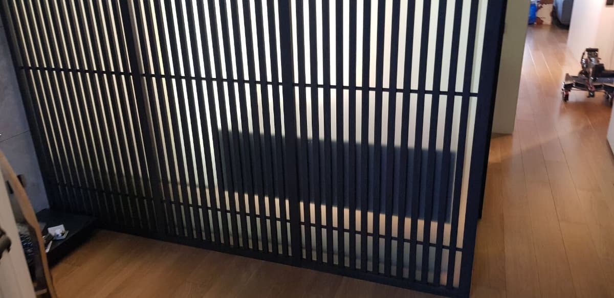 Реечная перегородка гардеробной — вид спереди, тёмное дерево от пола до потолка