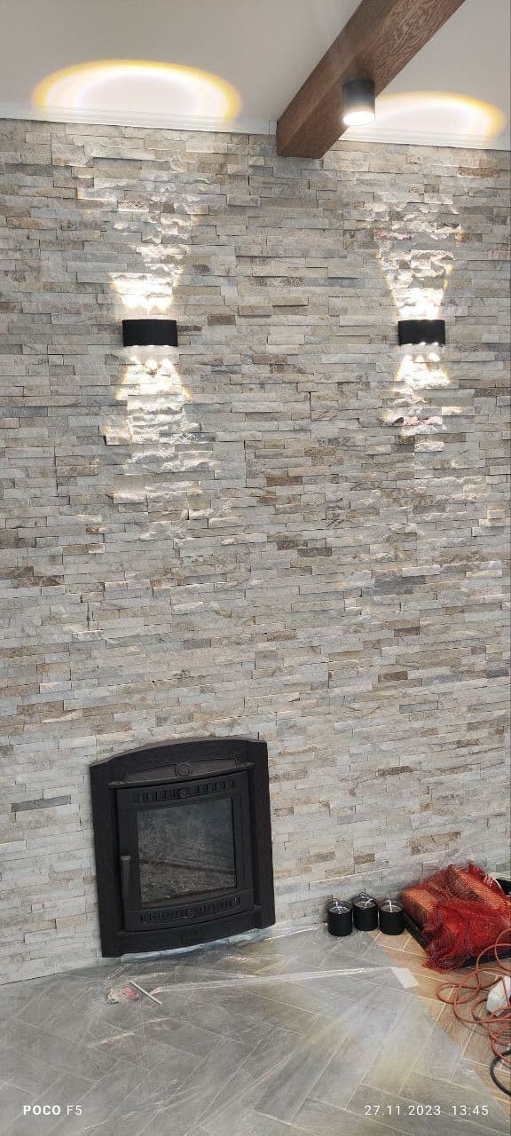 Камин с чугунной топкой — облицовка натуральным камнем, два бра, деревянная балка